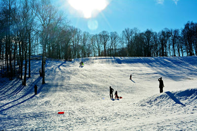 People playing on snow field against sky during winter