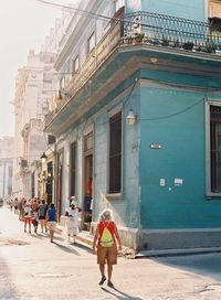 Rear view of people walking on street amidst buildings