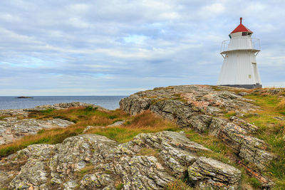 Lighthouse by sea against sky