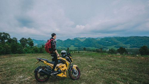 Man riding bicycle on field against sky