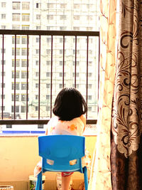 Rear view of man looking through window