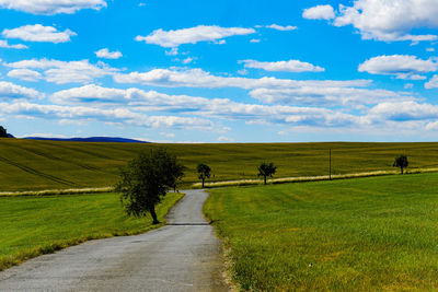 Road amidst field against sky