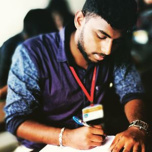 Young man writing exam in classroom