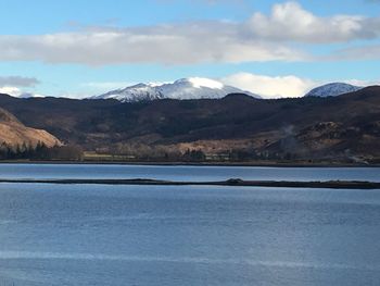 Scenic view of lake by snowcapped mountains against sky