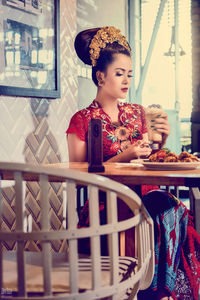 Young woman looking away while sitting on table at cafe