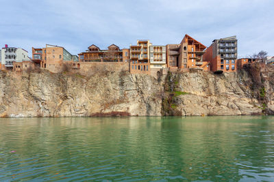 Buildings by river against sky