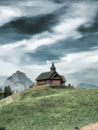 Built structure on field by mountain against sky
