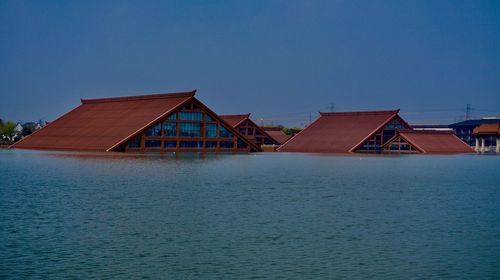 Houses by sea against clear blue sky