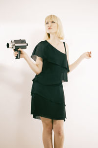 Portrait of young woman standing against white background