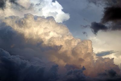 Low angle view of sunlight streaming through clouds