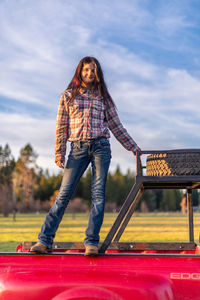 Portrait of young woman standing on truck bed