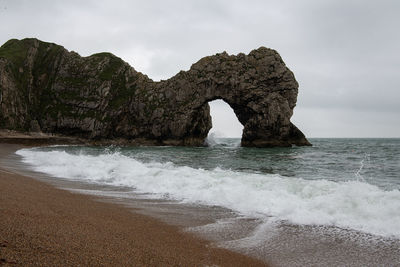 Rock formation on sea shore against sky