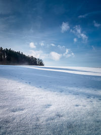 Scenic view of snow covered land against blue sky