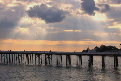 Pier over sea against sky during sunset