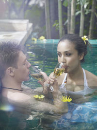 Close-up of couple having drink in swimming pool