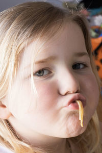 Close-up portrait of cute girl eating noodles