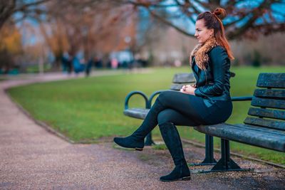 Side view of thoughtful young woman sitting on bench at park