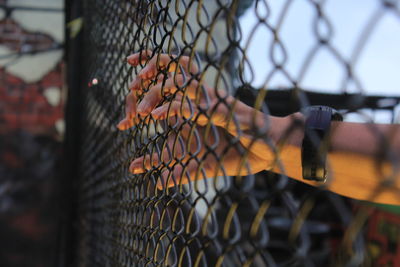 Close-up of hand on chainlink fence