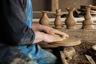 Midsection of potter molding a shape at workshop