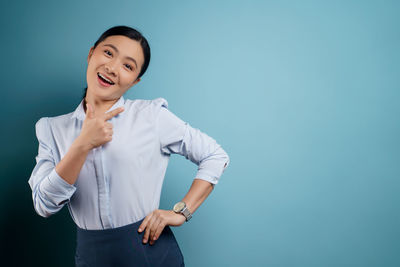 Smiling young woman standing against blue background