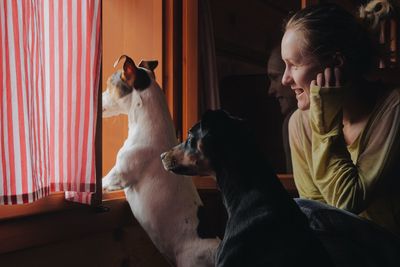 Rear view of woman sitting at home with dogs