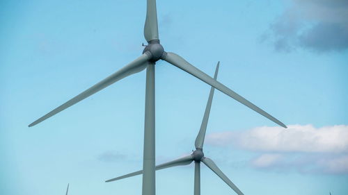 Low angle view of windmills against blue sky