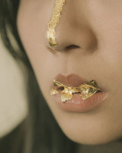 Close-up of woman face with golden foil on lips and nose