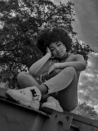 Full length of boy sitting on tree against plants