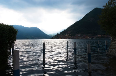 Wooden posts in lake against sky