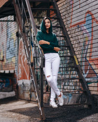 Portrait of young woman standing against building