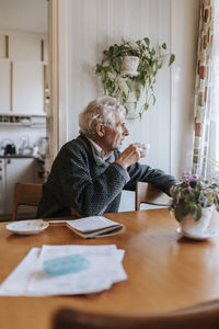 Senior man having tea while sitting at dining table in home