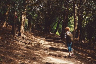 Rear view full length of woman standing by trees at park