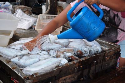 Cropped image of worker cleaning fish with watering can