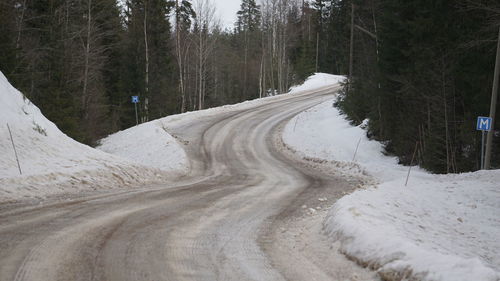 Road amidst trees in forest during winter