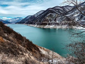 Scenic view of lake by snowcapped mountains against sky