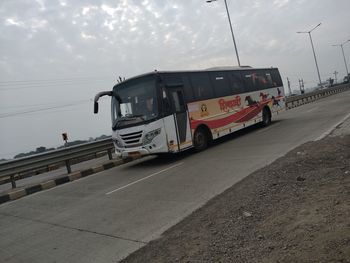 Vehicles on road against sky in city