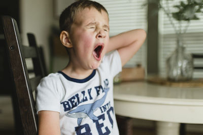 Young boy yawning at the table in the morning buda texas