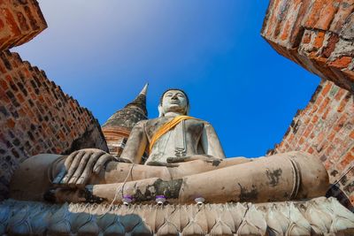 Low angle view of statue against historic building against sky