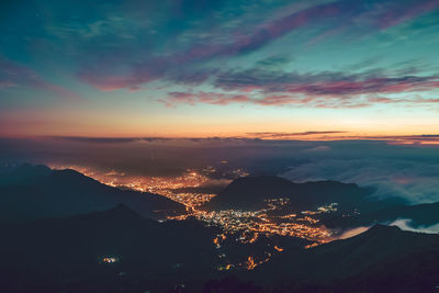 Aerial view of illuminated cityscape against sky during sunset