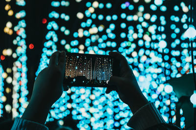 Man photographing illuminated mobile phone