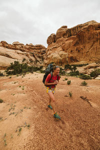 Smiling female backpacker walks through canyon floor near moab utah
