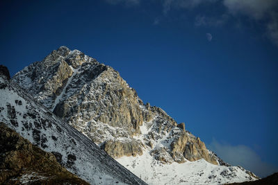 Low angle view of snowcapped mountain against blue sky