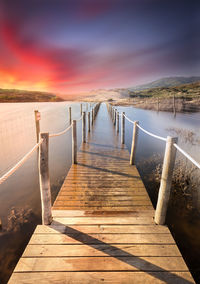 Wooden pier on sea against sky during sunset