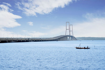 Bridge over sea against cloudy sky