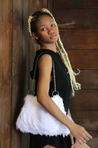 Portrait of woman standing by wooden wall