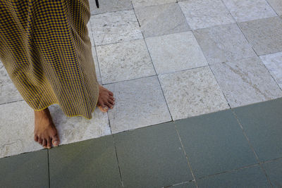 Low section of man weaeing longyi standing on tiled floor