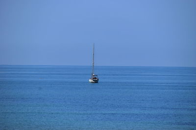 Sailboat sailing on sea against blue sky