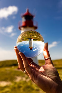 Midsection of person holding crystal ball against sky