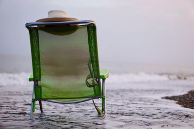 Close-up of chair on beach against sky