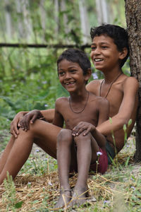 Full length of happy friends sitting on land